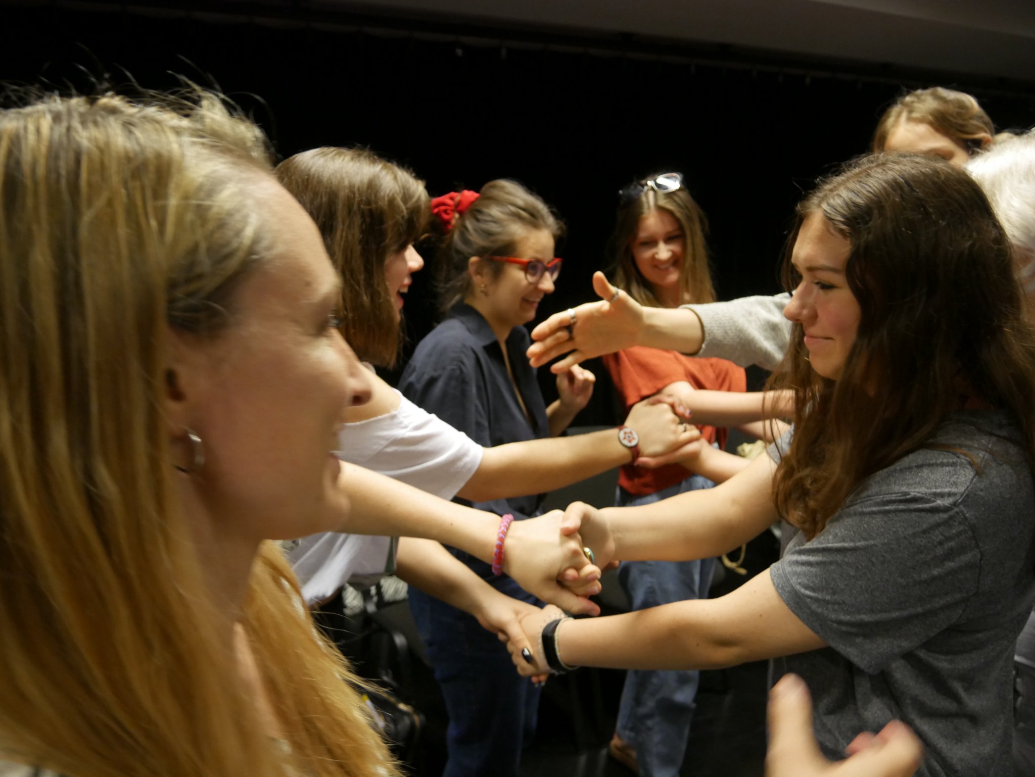Zdjęcie grupy osób z publiczności podczas spektaklu Teatru Legislacyjnego, którzy/re witają się poprzez podanie ręki.