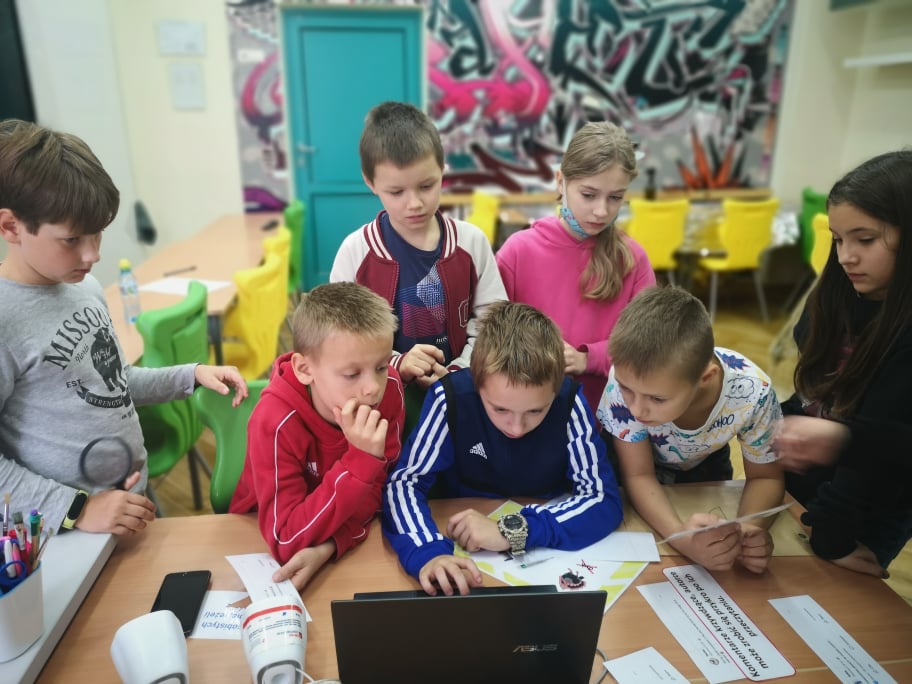 odnalezc sie w sieci 1 Zdjęcie przedstawiające 7 dzieci pochylające się nad komputerem i patrzące na niego z zaciekawieniem.
