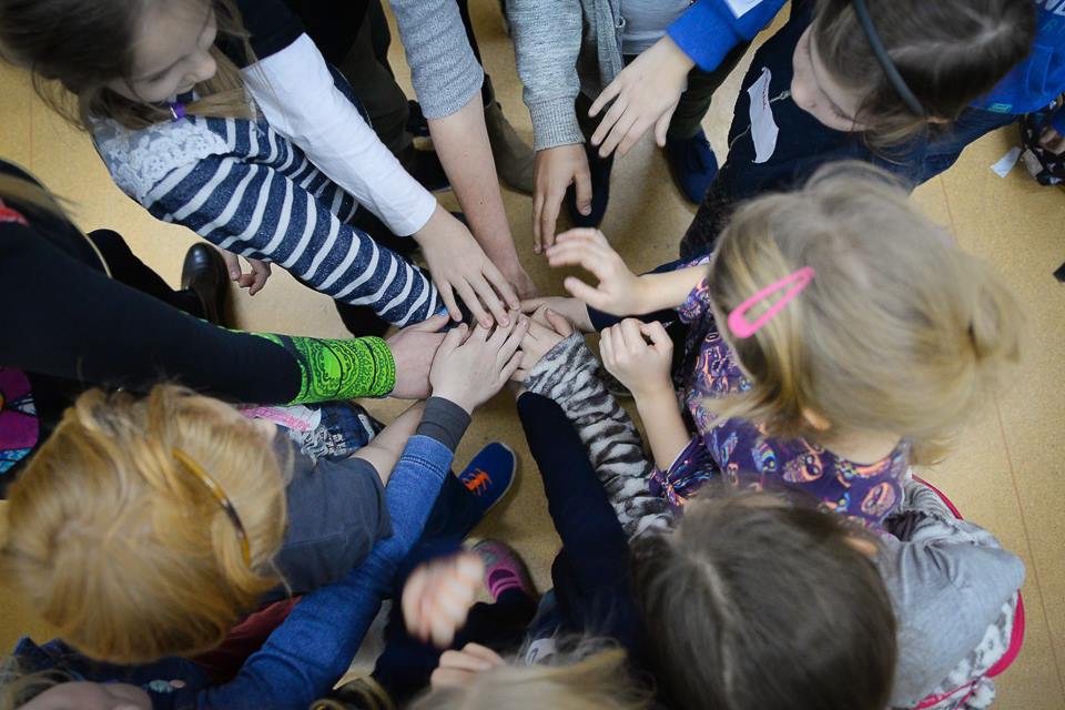 Dzieci trzymające dłonie w środku kręgu.